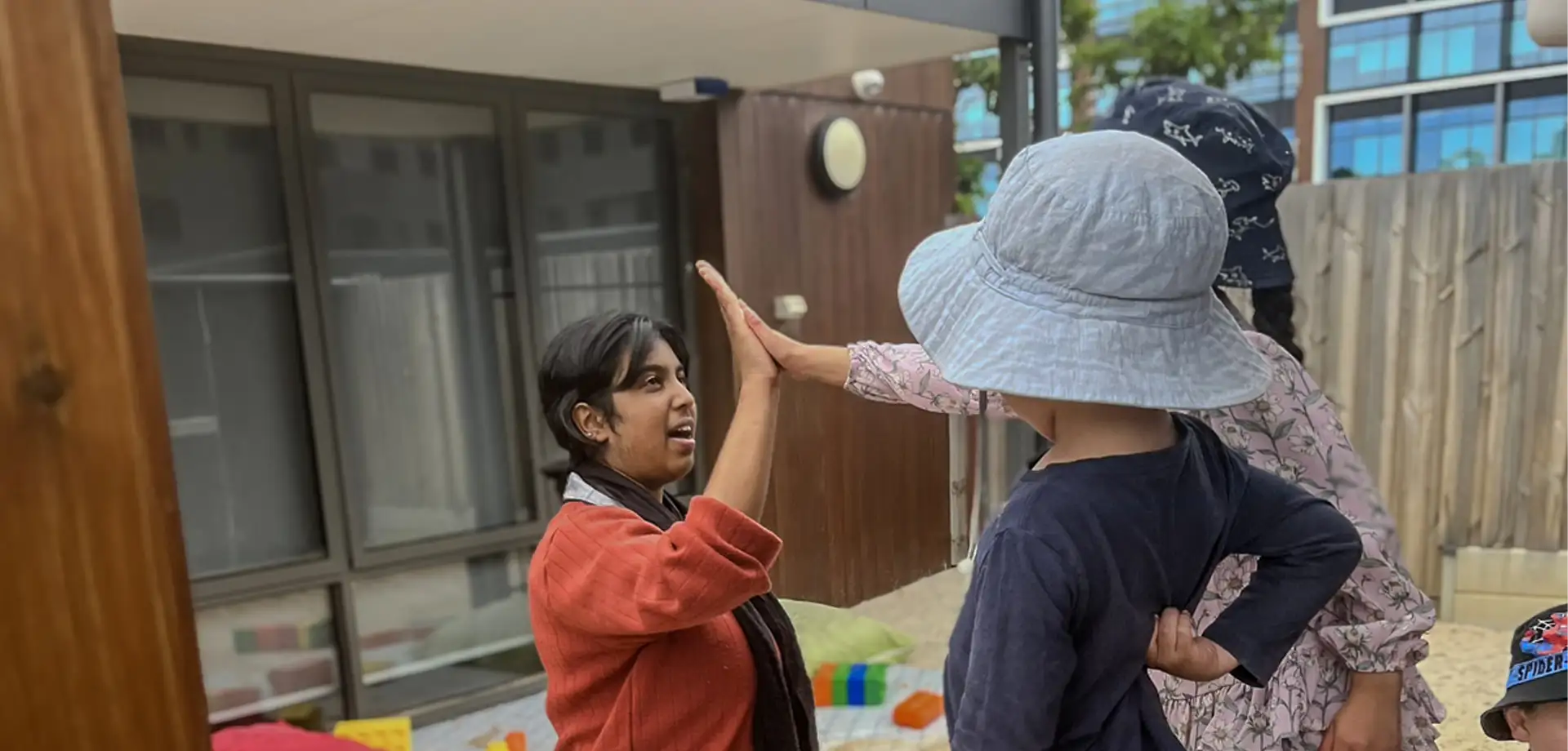 Secondary student giving a high five to two pre-school children