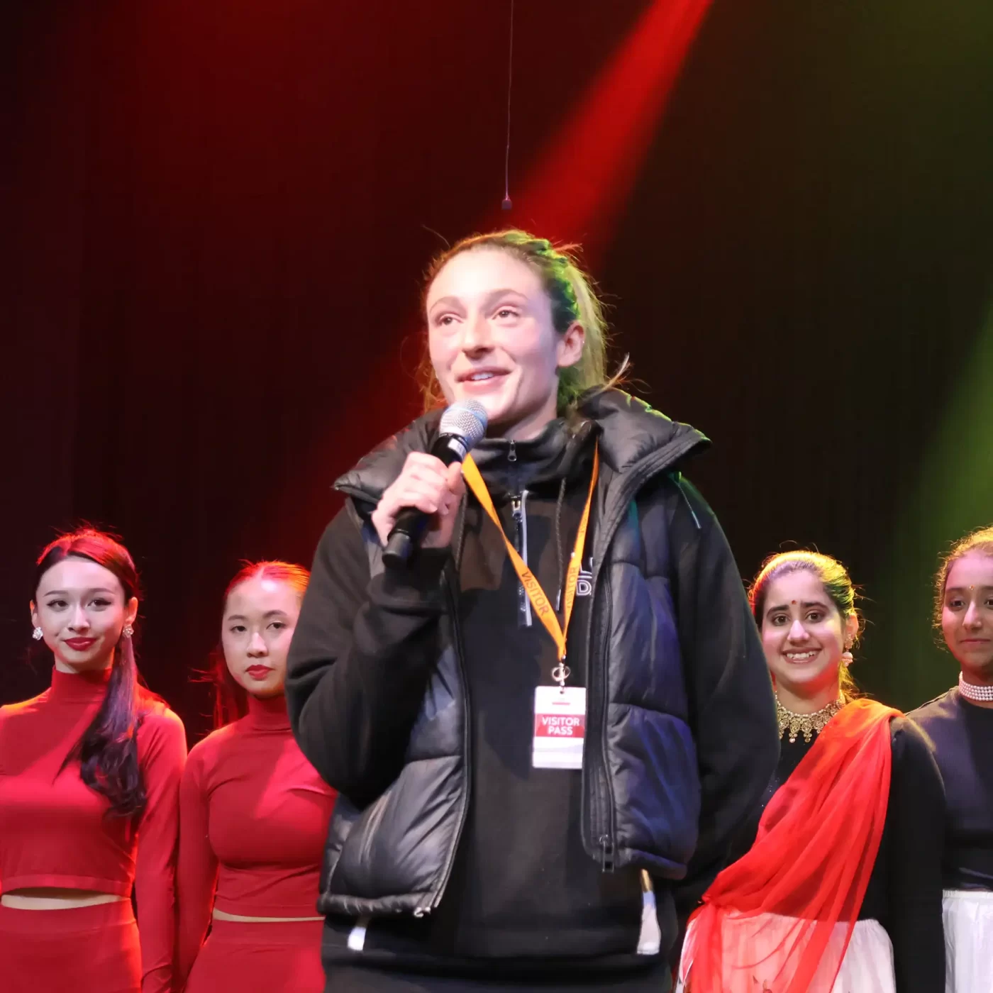 Woman holding a microphone in front of dancers