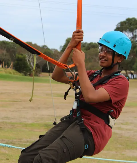 Male student in a harness on a ropes course