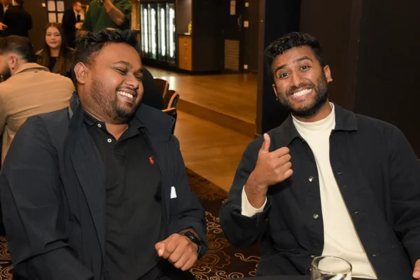 2 Alumni posing for a photo, one with a thumbs up